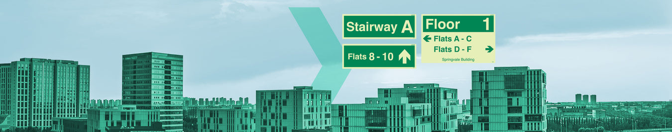 Directional signage for "Stairway A" and "Floor 1" with flat numbers, against an urban skyline.